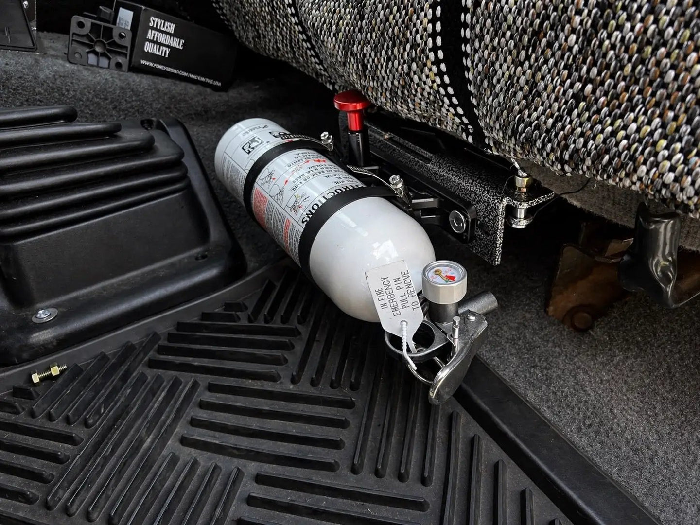 OBS Ford Fire Extinguisher Mount JC Customs—white extinguisher secured in black metal bracket under the seat