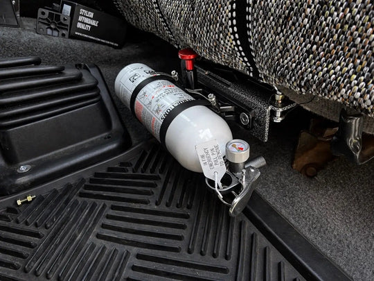 OBS Ford Fire Extinguisher Mount JC Customs—white extinguisher secured in black metal bracket under the seat