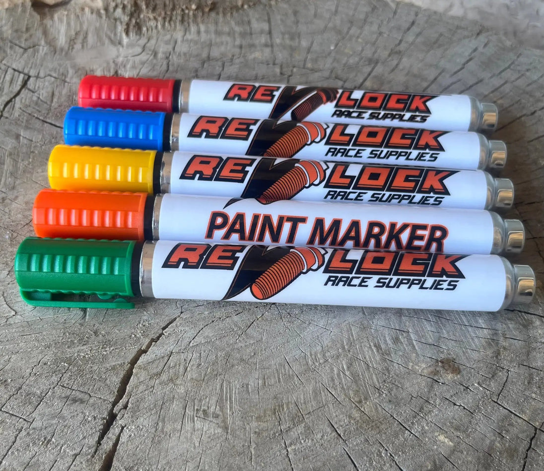 Revlock Race Supplies paint marker set, six color-coded markers with textured caps on a wooden surface