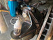 Sure-Lock 30ml white bottle by Revlock Race Supplies; two items: white bottle and blue anodized fitting in workshop.