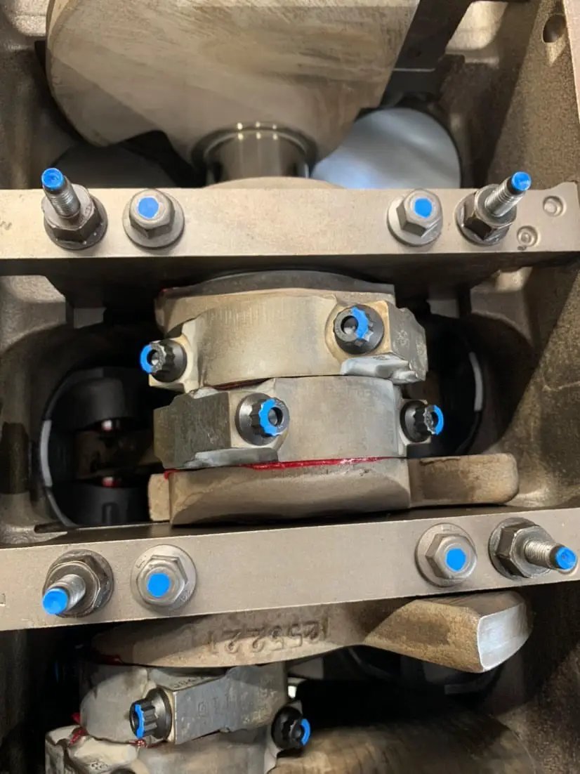 Paint marker by Revlock Race Supplies; metal industrial machinery with blue-tipped bolts.