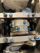 Paint marker by Revlock Race Supplies; metal industrial machinery with blue-tipped bolts.