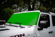 Solar shade for Jeep Wrangler/Gladiator; bright green windshield cover on white SUV, SpiderWebShade badge visible.