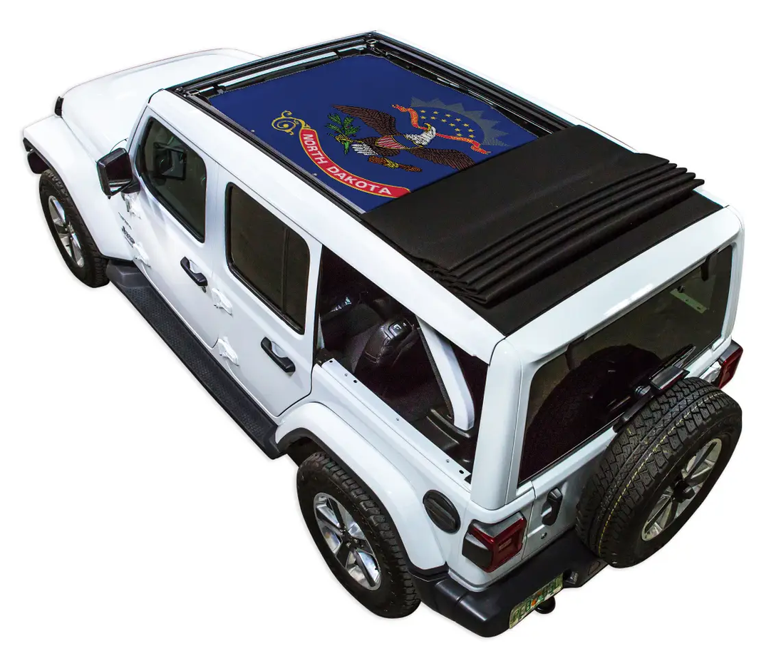 Sun shade top by SpiderWebShade for Jeep Wrangler JLU, blue North Dakota flag print on white Jeep with folded black shade.