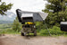 Smittybilt Overland X L hard shell tent mounted on roof rack of rugged off-road vehicle; gray with white panels