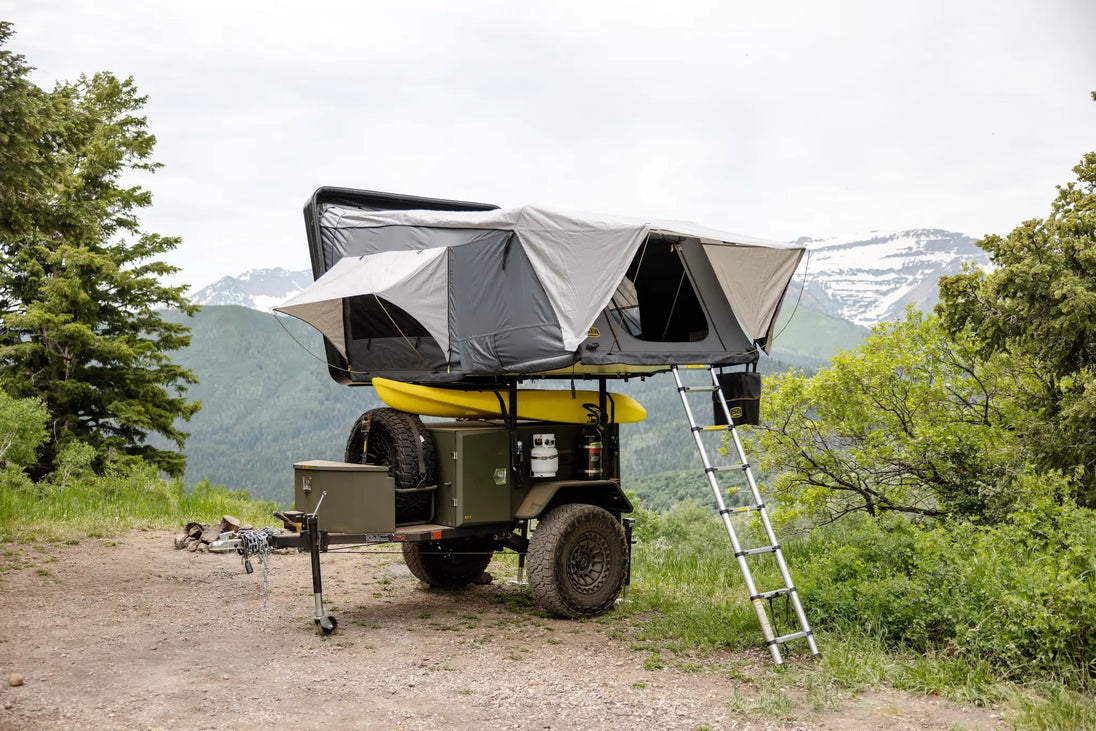 Smittybilt Overland X L hard-shell tent in gray on an off-road vehicle with ladder