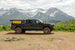 Aluminum side-opening roof top tent by Smittybilt mounted on a black pickup with mountain backdrop