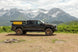 Aluminum side-opening roof top tent by Smittybilt mounted on a black pickup with mountain backdrop