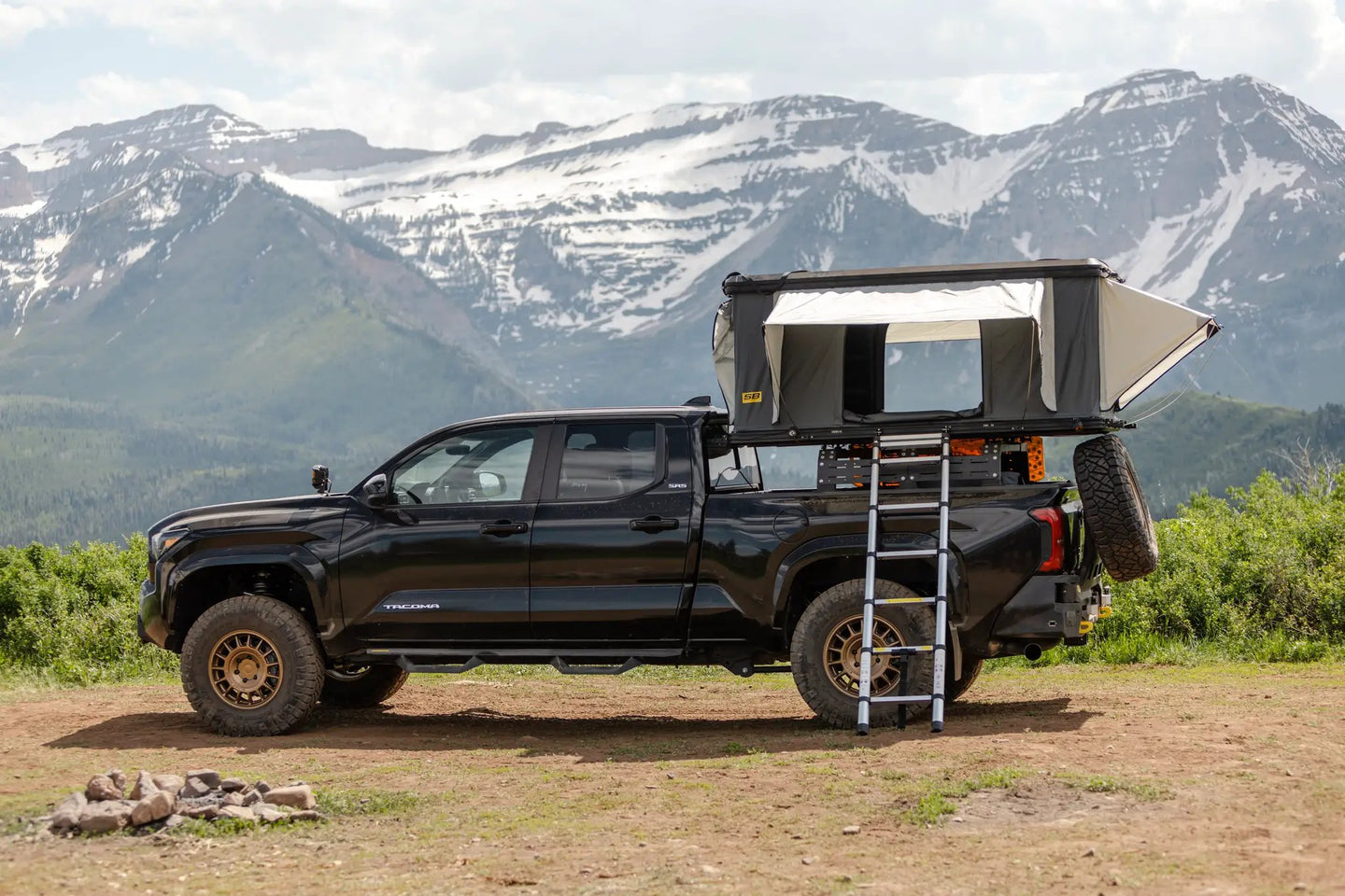 Aluminum Side Opening Roof Top Tent by Smittybilt on a black Toyota Tacoma with ladder