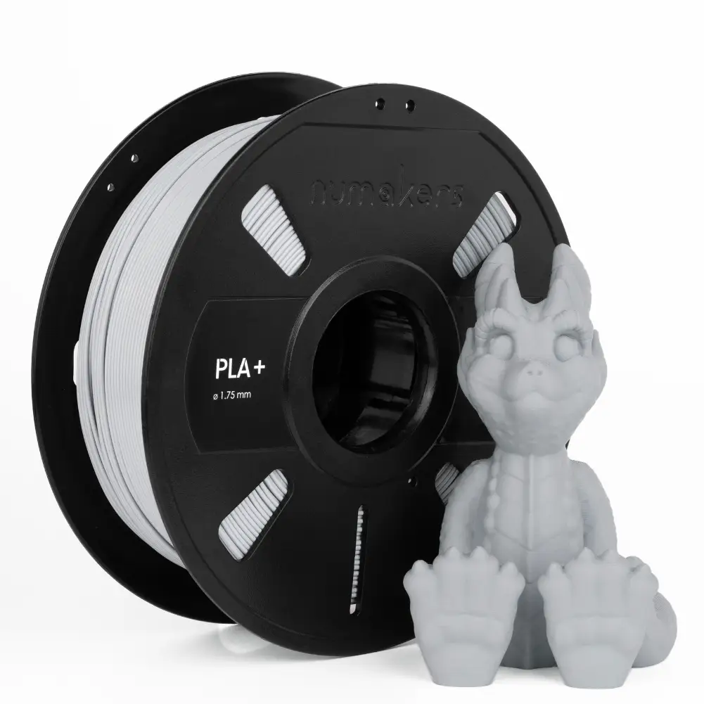 PLA+ Filament spool by Numakers; black spool with gray filament and a small dragon figurine beside it.
