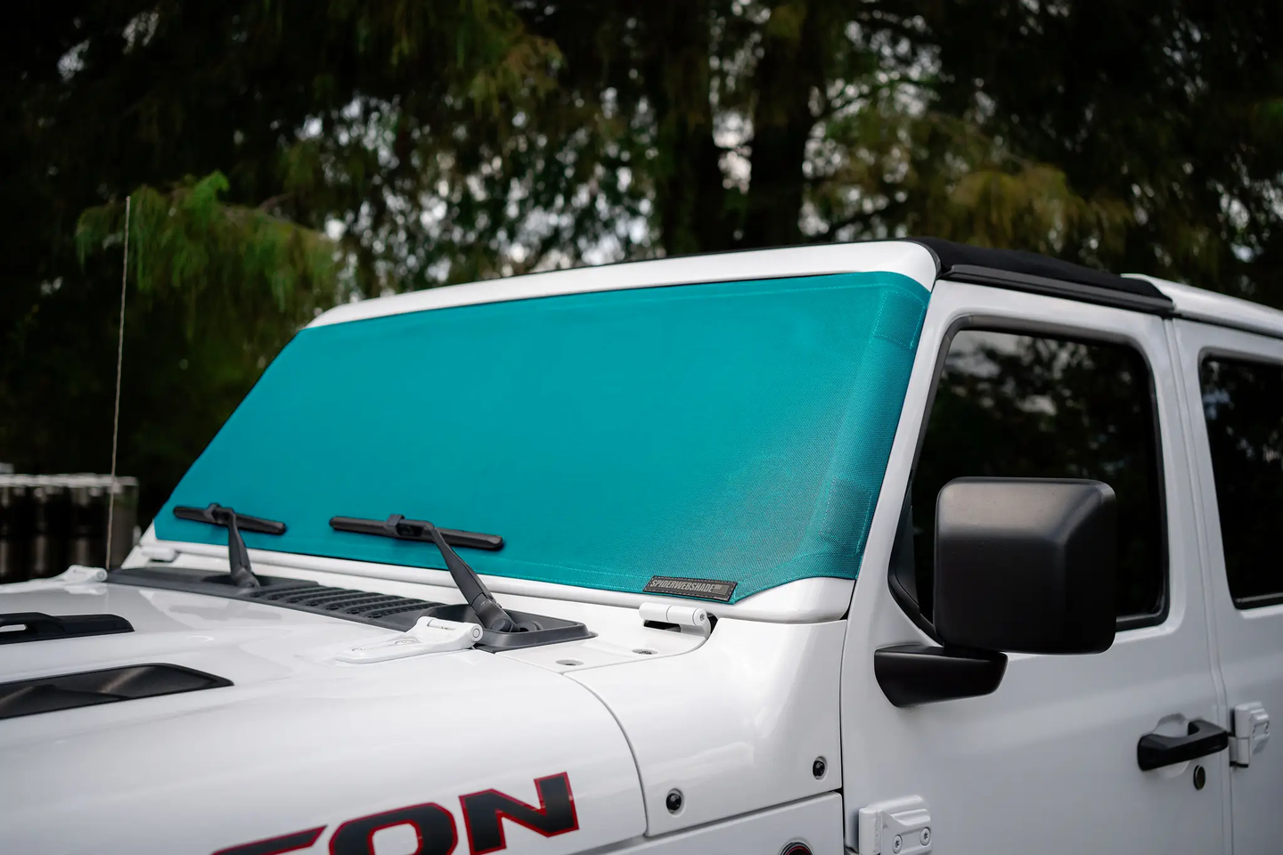 Solar shade for Jeep Wrangler/Gladiator by SpiderWebShade; teal window shade fitted on white Jeep.
