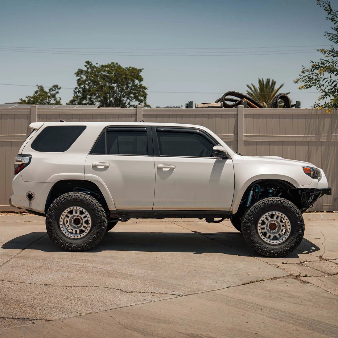 Dirt King Long Travel Kit for Toyota; coilover suspension parts on fence with white Toyota SUV below