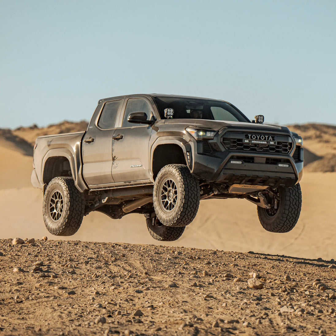 Dirt King 2.5 Coilovers DCA Remote Reservoir Toyota Tacoma front suspension visible in desert off-road scene